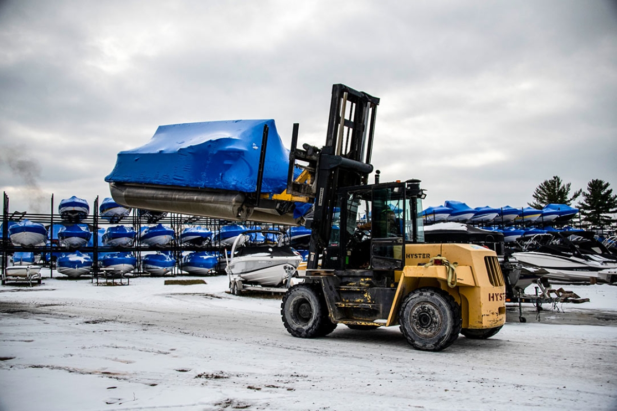 Forklift carrying a shrink wrapped pontoon in the winter